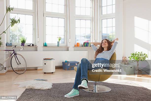 relaxed woman at home sitting in chair - chair fotografías e imágenes de stock