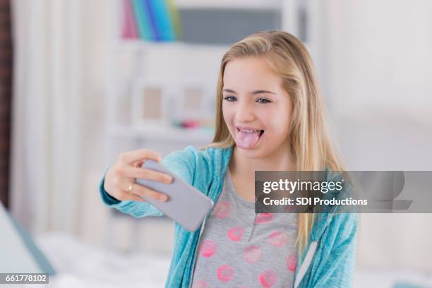 preteen girl makes a silly face while taking selfie - blonde girl sticking out her tongue stock pictures, royalty-free photos & images