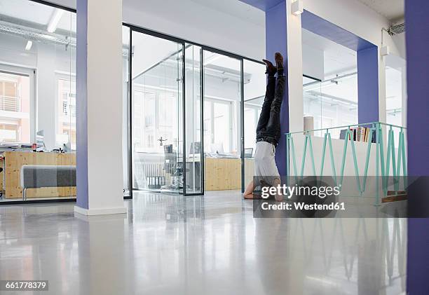 businessman doing headstand against wall in office - office yoga stock pictures, royalty-free photos & images