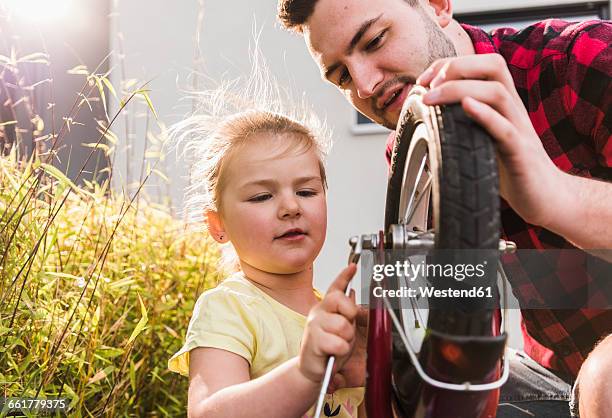 father and daughter repairing bicycle together - bicycle daughter stock-fotos und bilder