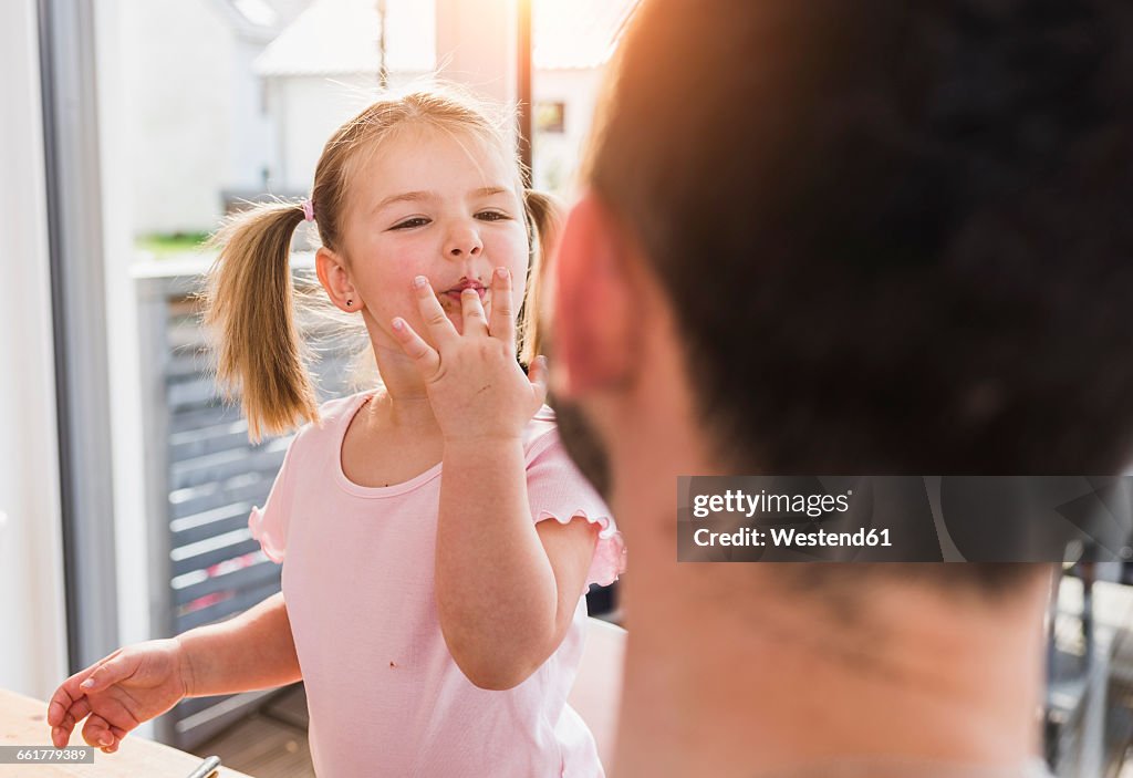 Girl with finger in mouth looking at father