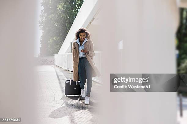 young woman with luggage and cell phone on the move - business travel stock pictures, royalty-free photos & images