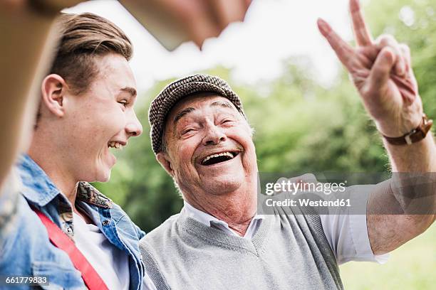 grandfather and grandson taking selfie with smartphone - victory sign stock-fotos und bilder