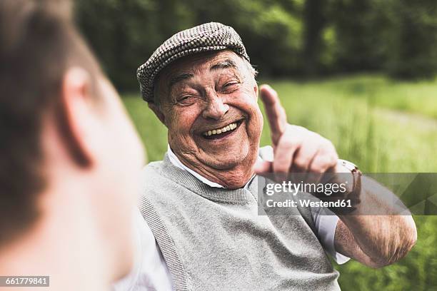 portrait of laughing senior man talking to his grandson - uomo anziano felice foto e immagini stock