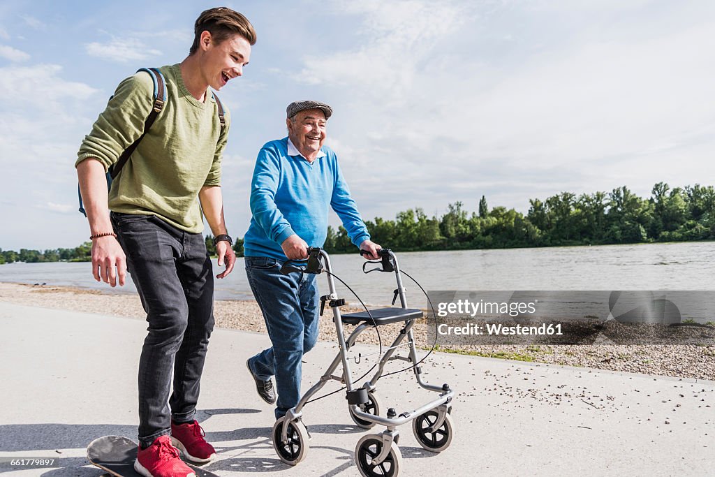 Grandfather and grandson strolling together at riverside