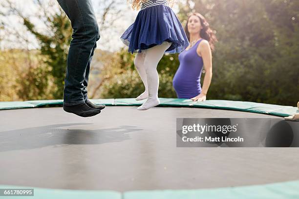 low section of father and daughter bouncing on trampoline - trampoline stock pictures, royalty-free photos & images