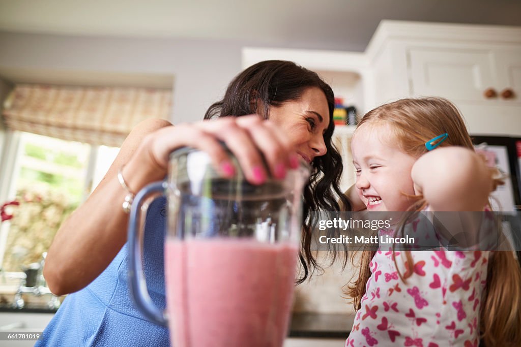 Mother and daughter making smoothies in noisy blender