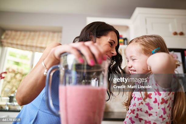 mother and daughter making smoothies in noisy blender - smoothie stock-fotos und bilder