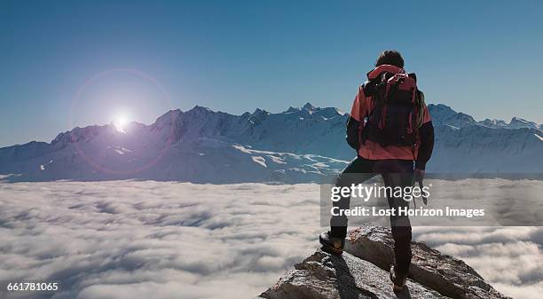 climber looking out at sunset from peak emerging from fog, bettmeralp, valais, switzerland - valais canton stock pictures, royalty-free photos & images