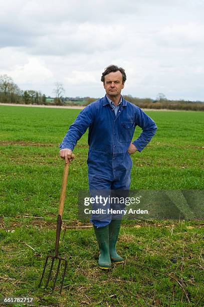 portrait of farmer leaning on pitch fork in field - fourche photos et images de collection