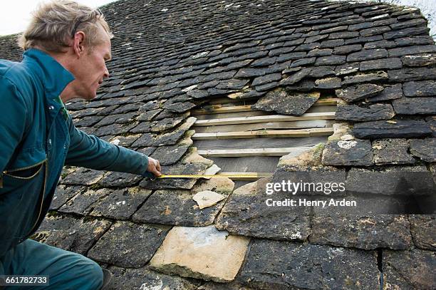 roofer measuring hole in traditional stone tile roof - roofer stock pictures, royalty-free photos & images