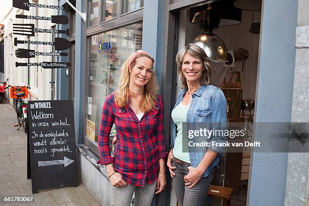 women standing in shop doorway looking at camera smiling - chemise à carreaux photos et images de collection