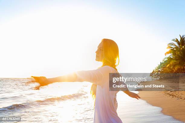 young woman dancing on beach at sunset, dominican republic, the caribbean - caribbean dream stock pictures, royalty-free photos & images