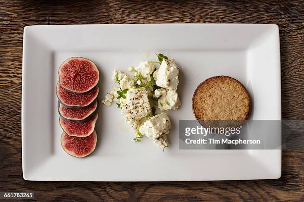 overhead view of feta, figs and crackers on cheese board - lebensmittel rechteck stock-fotos und bilder