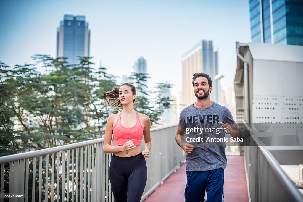 Running couple running on footbridge, Dubai, United Arab Emirates