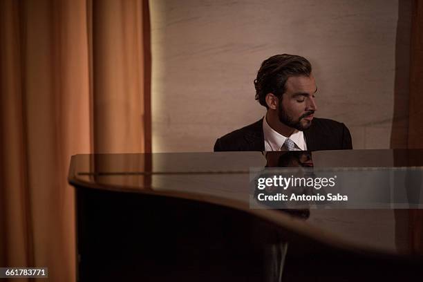 young man playing piano in bar at night - fabolous musician stockfoto's en -beelden