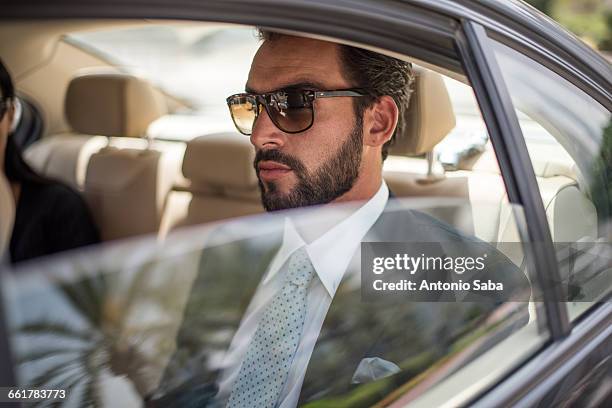 young businessman wearing sunglasses in car backseat, dubai, united arab emirates - arab car stock pictures, royalty-free photos & images