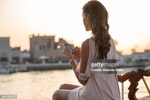 woman reading smartphone texts on boat at dubai marina, united arab emirates - dubai tourist stock pictures, royalty-free photos & images