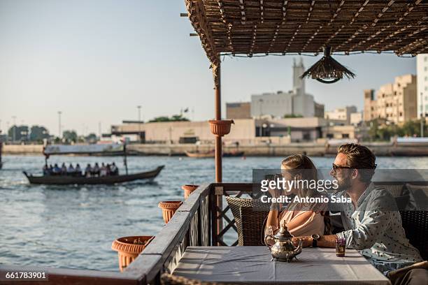 romantic couple photographing from dubai marina cafe, united arab emirates - couples dubai stock pictures, royalty-free photos & images