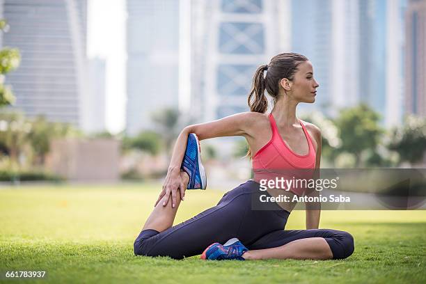woman practicing yoga pose in park, dubai, united arab emirates - yoga office arab stock pictures, royalty-free photos & images