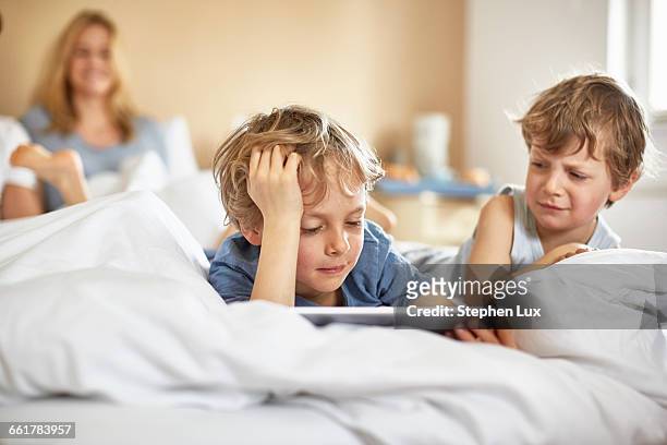 boys on parents bed using digital tablet - annoying brother stock pictures, royalty-free photos & images