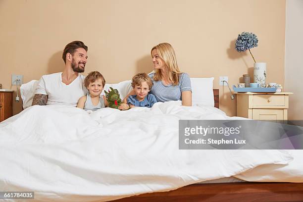 mother and father in bed with sons and toy dragon - white dragon tattoo stock pictures, royalty-free photos & images