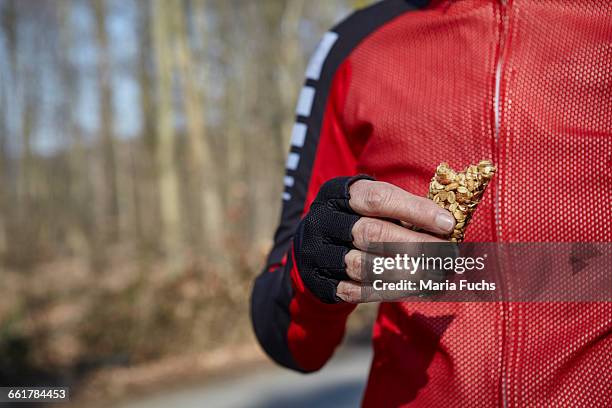 cropped view of woman wearing fingerless gloves holding protein bar - muesli bar stock pictures, royalty-free photos & images