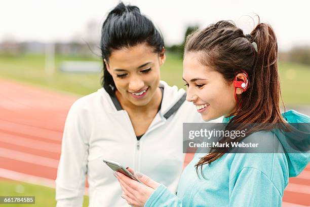 two young women beside running track, looking at smartphone - live at leeds 2016 stock-fotos und bilder