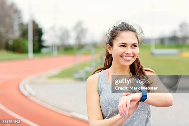 young woman beside running track, checking watch, smiling - live at leeds 2016 stock pictures, royalty-free photos & images