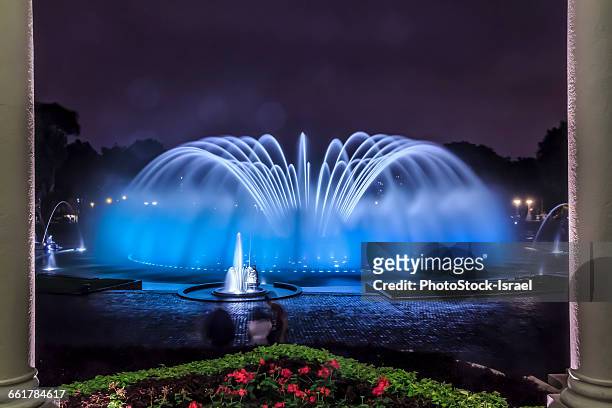 blue illuminated fountain at night, park of the reserve (parque de la reserva), lima, peru - fuente estructura creada por el hombre fotografías e imágenes de stock