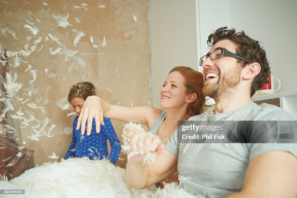 Mid adult couple pillow fighting daughter in bed