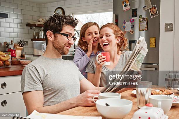 mid adult man at breakfast table reading newspaper whilst daughter and mother laughing - breakfast fathers bildbanksfoton och bilder