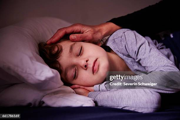 mothers hand stroking sleeping boy - consolare foto e immagini stock