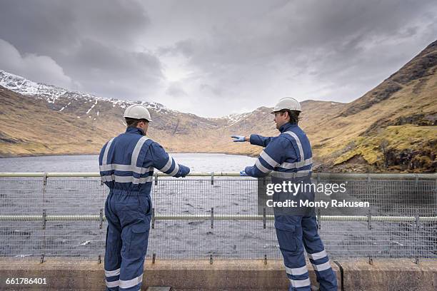 workers on dam with water at hydroelectric power station - wasser industrie stock-fotos und bilder