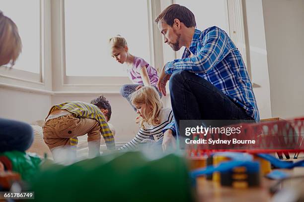 father watching children play, low angle view - modelleisenbahn stock-fotos und bilder