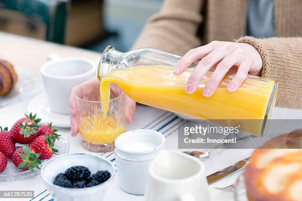 cropped view of woman pouring orange juice from bottle into glass - fruit juice stock pictures, royalty-free photos & images