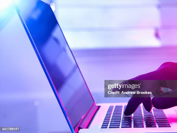 gloved hand hacking laptop computer - suspicion office stock pictures, royalty-free photos & images