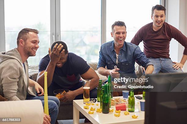 group of men watching sports event on television with snacks and beers smiling - sports event stock pictures, royalty-free photos & images