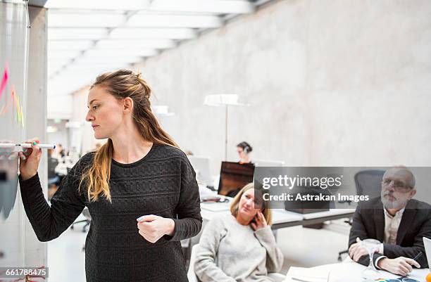 businesswoman giving presentation to colleagues in creative office - transparent wipe board stock pictures, royalty-free photos & images