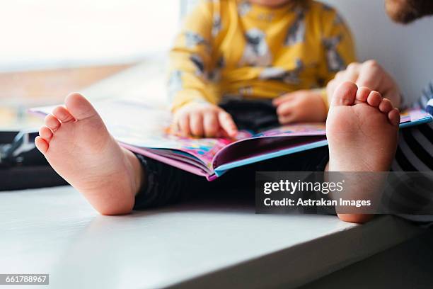 cropped image of father and daughter with picture book at home - 2 year old book stock pictures, royalty-free photos & images