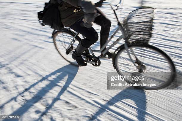 low section of person riding bicycle on snow covered street - bicycle tire stock pictures, royalty-free photos & images