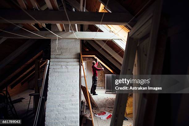 side view of man working in attic under construction - attic conversion stock pictures, royalty-free photos & images