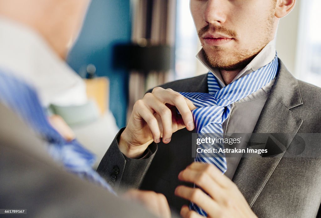 Businessman wearing tie in front of mirror at hotel room