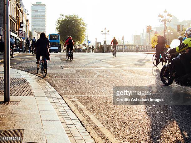people riding bicycles on city street - dublin bus foto e immagini stock