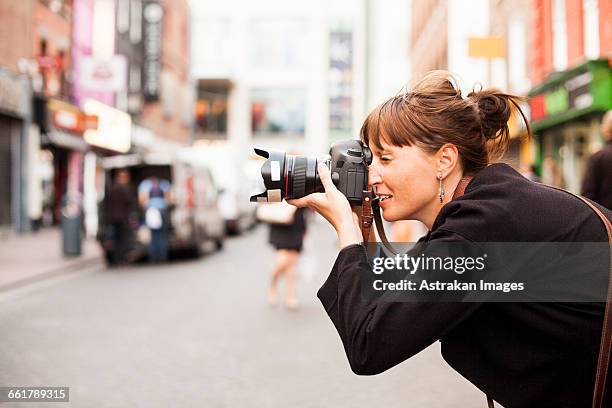 side view of woman photographing on city street - photographer fotografías e imágenes de stock