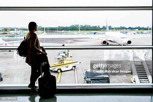 full length side view of businesswoman looking through glass window at airport - dublin airport stock pictures, royalty-free photos & images