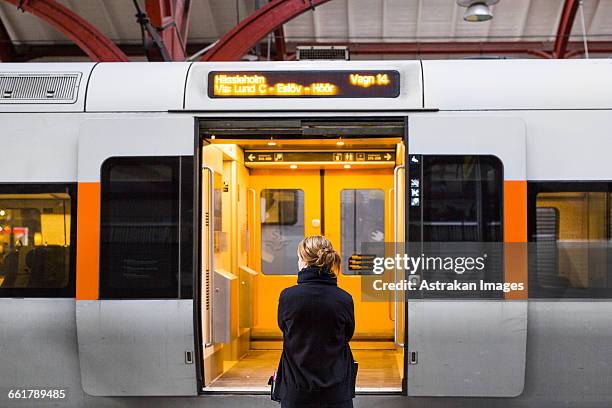 rear view of woman standing against train at railroad station - vehicle door stock pictures, royalty-free photos & images