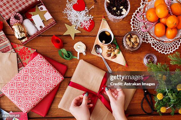 cropped image of hands tying bow on christmas present at wooden table - personal perspective festival stock pictures, royalty-free photos & images