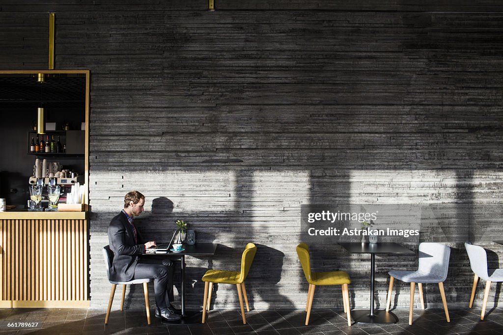 Side view of businessman using laptop while sitting at table