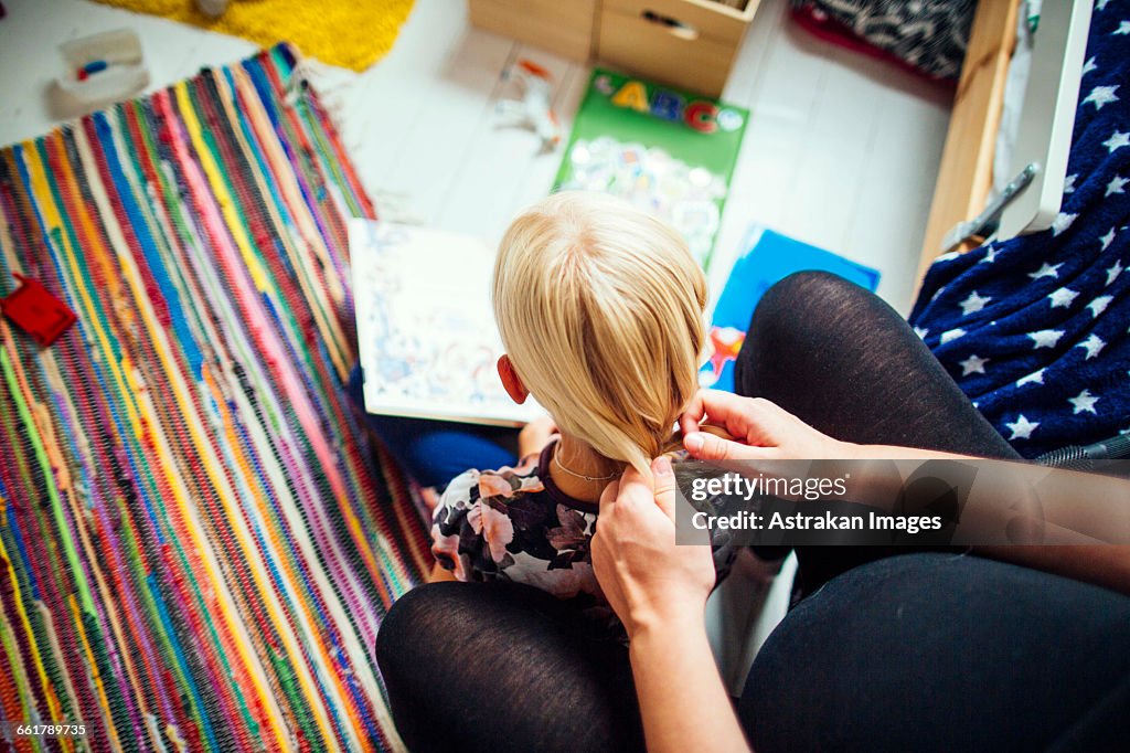 High angle view of mother braiding daughters hair at home